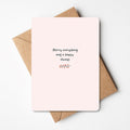 Minimalistische kerstkaart met de tekst "Merry everything and a happy always" en een klein takje met rode besjes, liggend op een bruine envelop.
