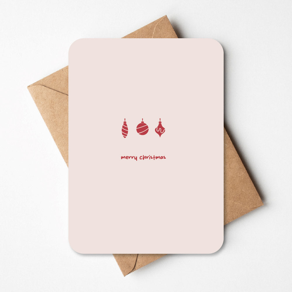  Kerstkaart met een minimalistisch ontwerp van kerstballen, liggend op een bruine envelop.