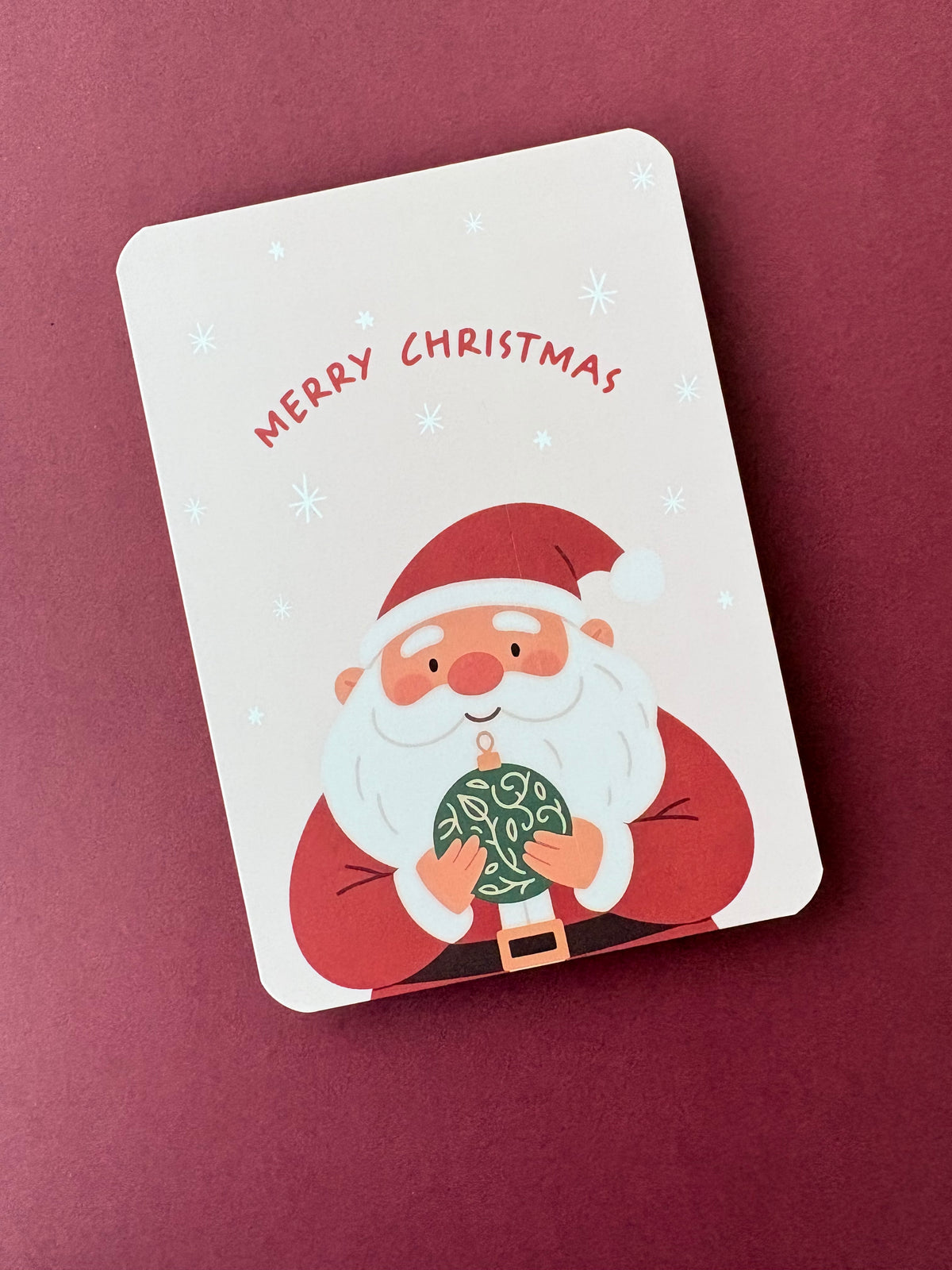 Kerstkaart met illustratie van kerstman die een kerstbal vasthoud