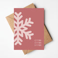 Rode kerstkaart met grote sneeuwvlok op en teks let it snow